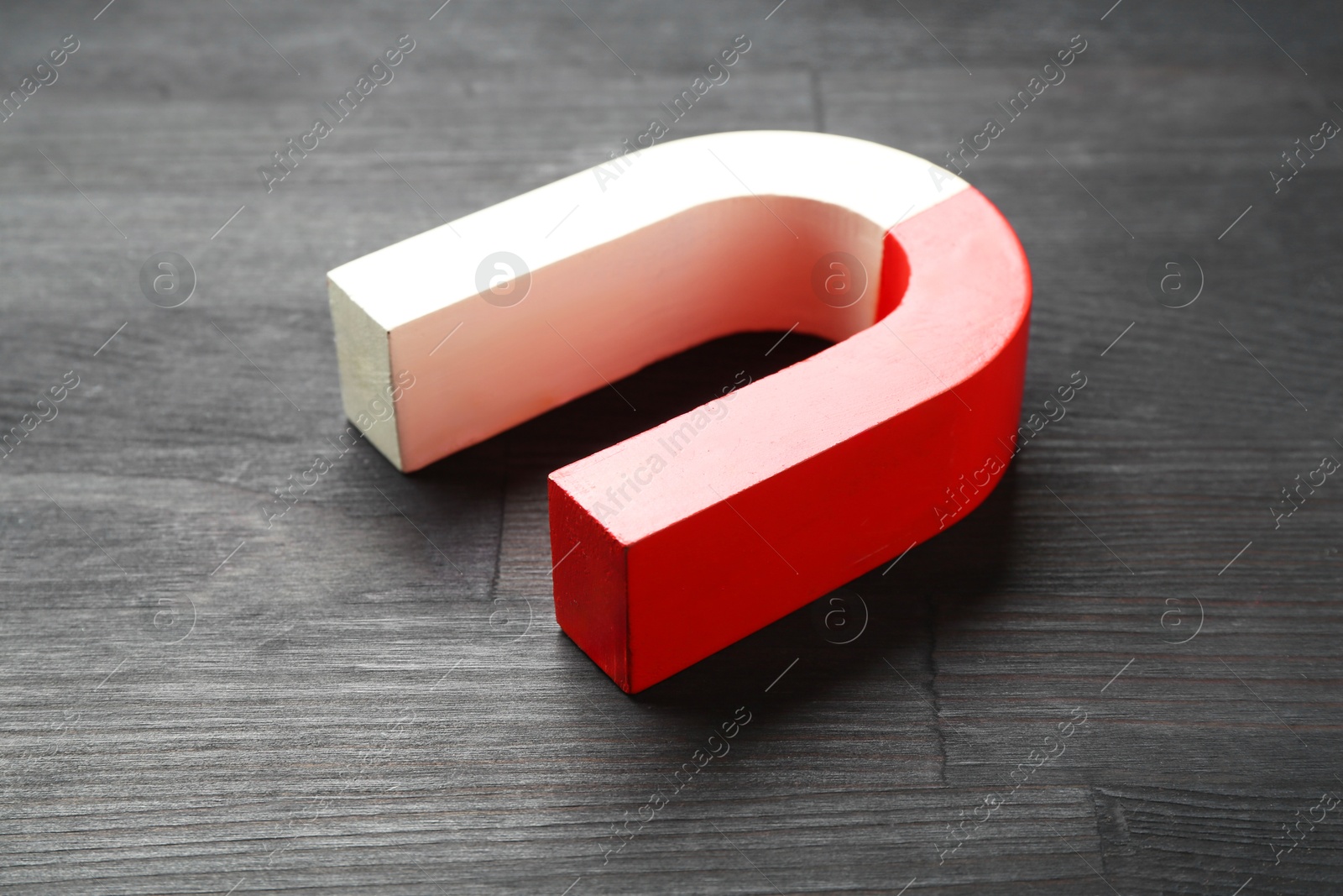 Photo of One horseshoe magnet on black wooden table, closeup