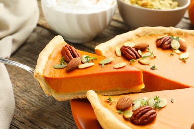 Photo of Taking piece of tasty homemade pumpkin pie at wooden table, closeup