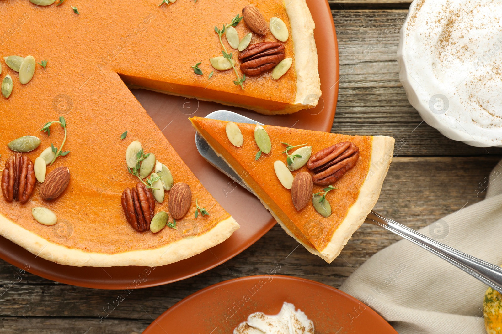 Photo of Taking piece of tasty homemade pumpkin pie at wooden table, top view