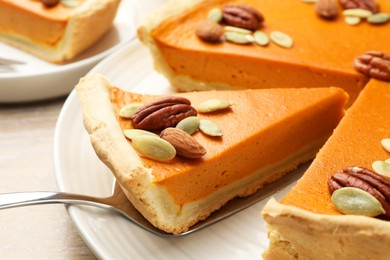 Photo of Taking piece of tasty homemade pumpkin pie at table, closeup