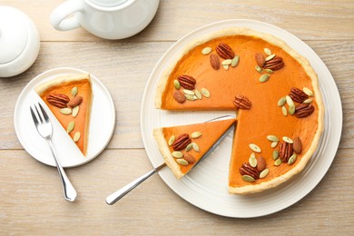 Photo of Tasty homemade pumpkin pie served on wooden table, top view