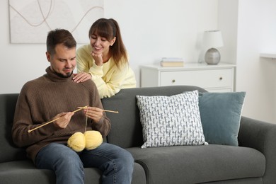 Woman teaching her boyfriend how to knit at home