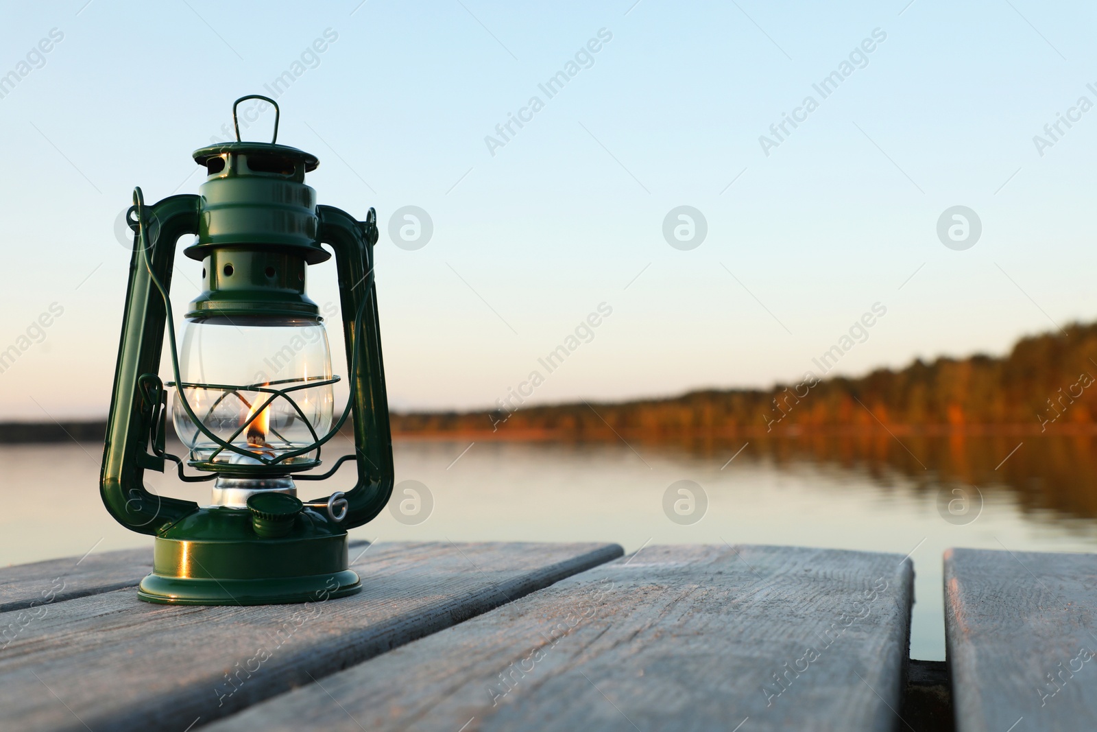 Photo of Vintage kerosene lamp on wooden surface in evening. Space for text