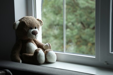 Photo of Lonely teddy bear near window. Space for text