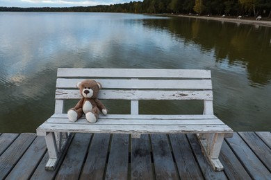 Photo of Lonely teddy bear on bench near river