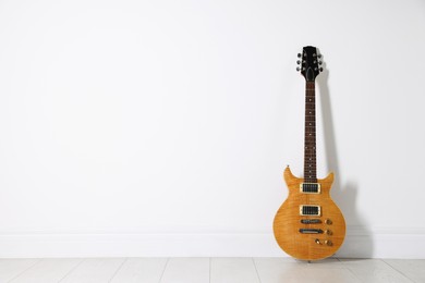 Photo of One modern electric guitar near white wall. Space for text