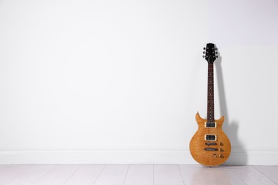 Photo of One modern electric guitar near white wall. Space for text