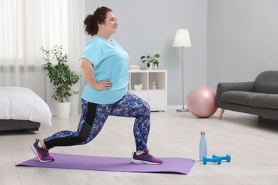 Photo of Plus size woman exercising on fitness mat at home