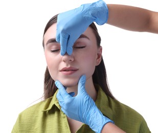 Photo of Doctor checking patient's nose before plastic surgery operation on white background, closeup