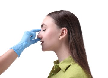 Photo of Doctor checking patient's nose before plastic surgery operation on white background, closeup