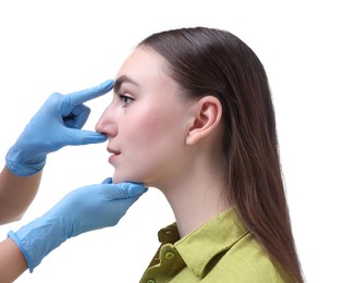 Doctor checking patient's nose before plastic surgery operation on white background, closeup