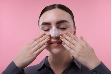 Photo of Woman with medical bandage on her nose after plastic surgery operation against pink background