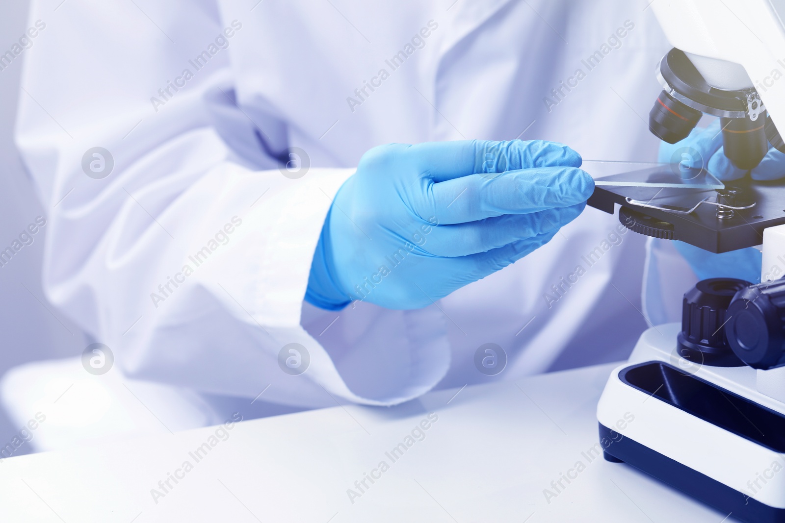 Photo of Scientist working with microscope at table in laboratory, closeup