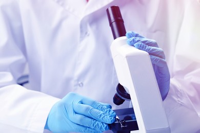 Photo of Scientist working with microscope in laboratory, closeup