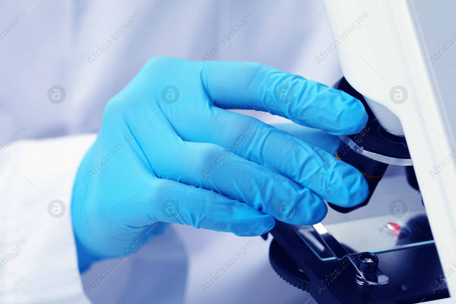 Photo of Scientist examining sample on slide under microscope, closeup