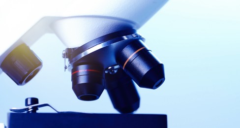 Photo of Science. Modern microscope on light blue background, closeup. Space for text