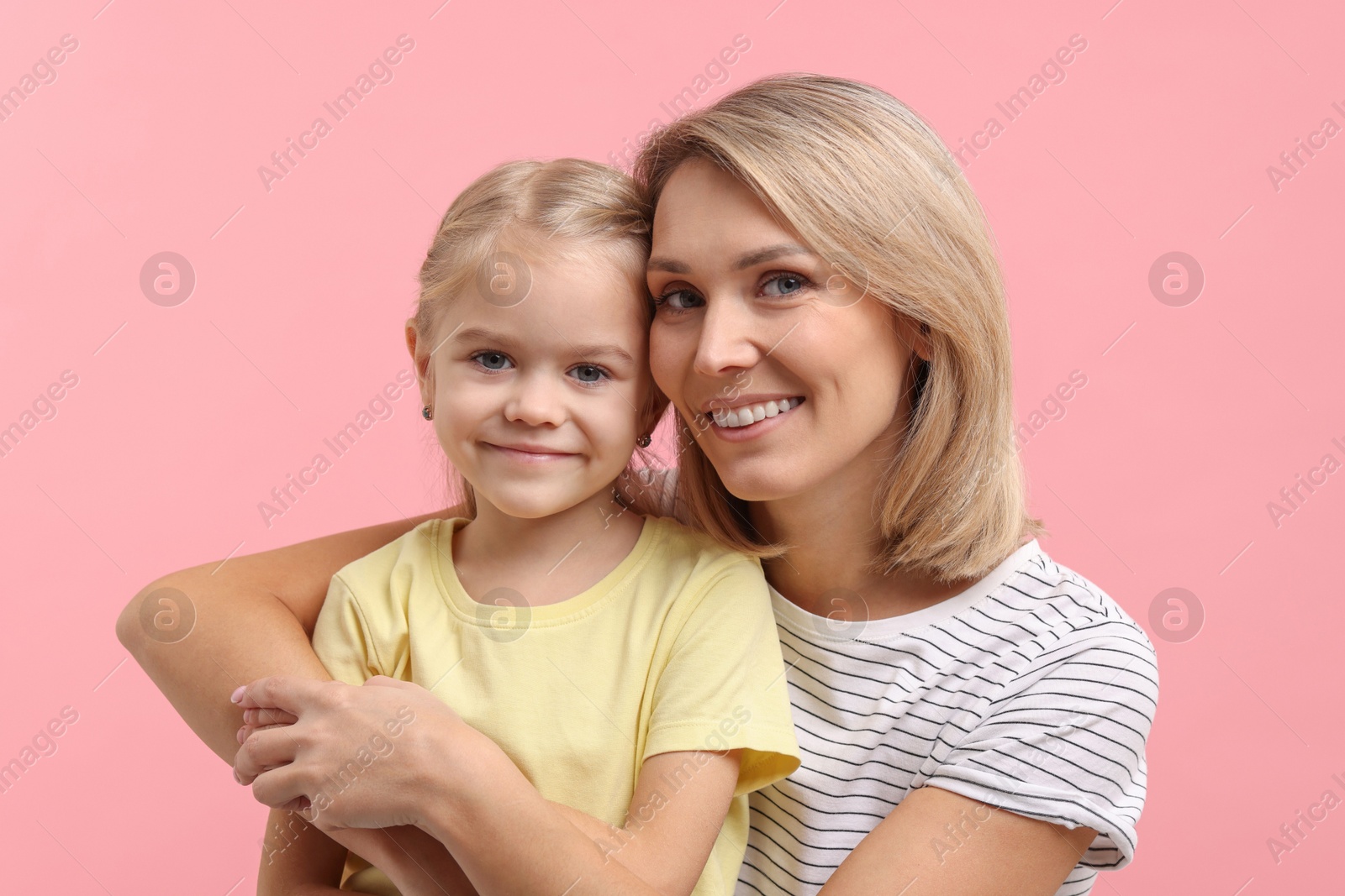 Photo of Cute little girl with her mom on pink background. Happy Mother's Day