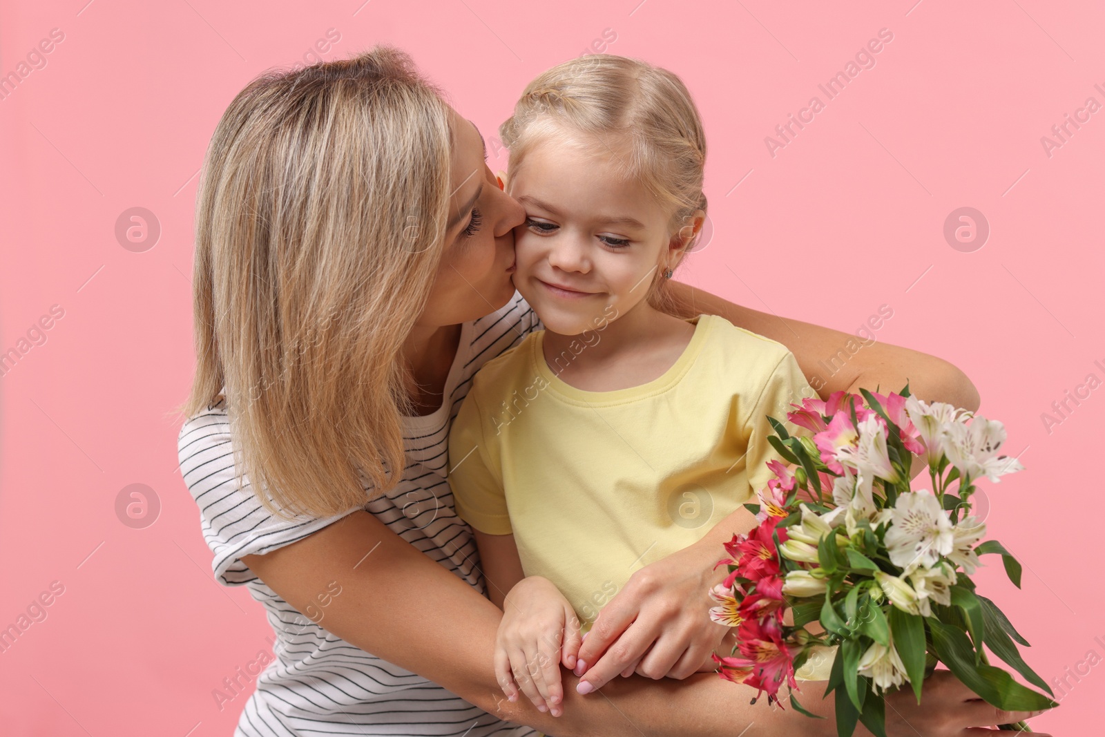 Photo of Little daughter congratulating her mom with bouquet of alstroemeria flowers on pink background. Happy Mother's Day