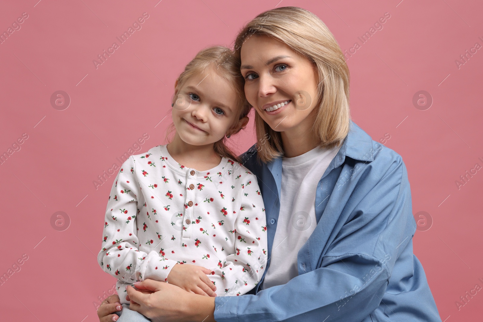 Photo of Cute little girl with her mom on pink background. Happy Mother's Day