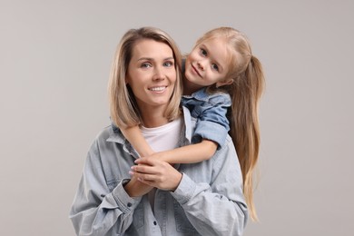 Photo of Cute little girl with her mom on gray background. Happy Mother's Day