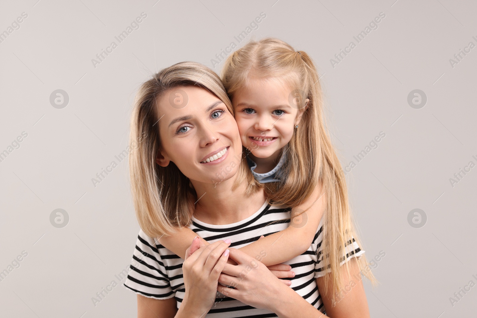 Photo of Cute little girl with her mom on gray background. Happy Mother's Day