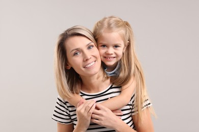 Cute little girl with her mom on gray background. Happy Mother's Day