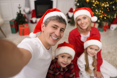 Photo of Happy family taking selfie together in Santa hats at home. Christmas season