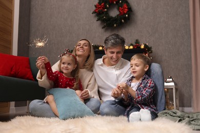 Photo of Lovely family with Christmas sparklers at home