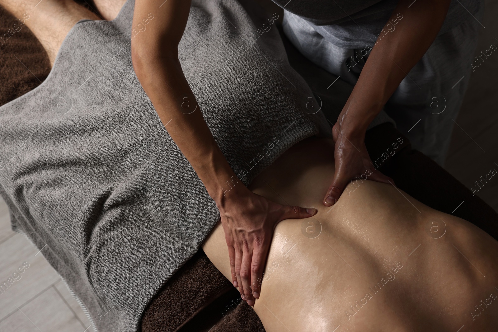 Photo of Professional physiotherapist doing massage for his client indoors, above view