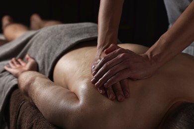 Photo of Professional physiotherapist doing shoulder massage for his client indoors, closeup