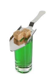 Photo of Absinthe in shot glass, brown sugar cubes and slotted spoon isolated on white