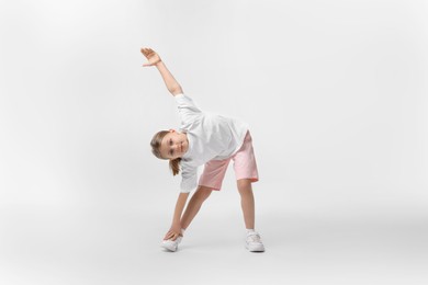 Photo of Cute little girl exercising on white background