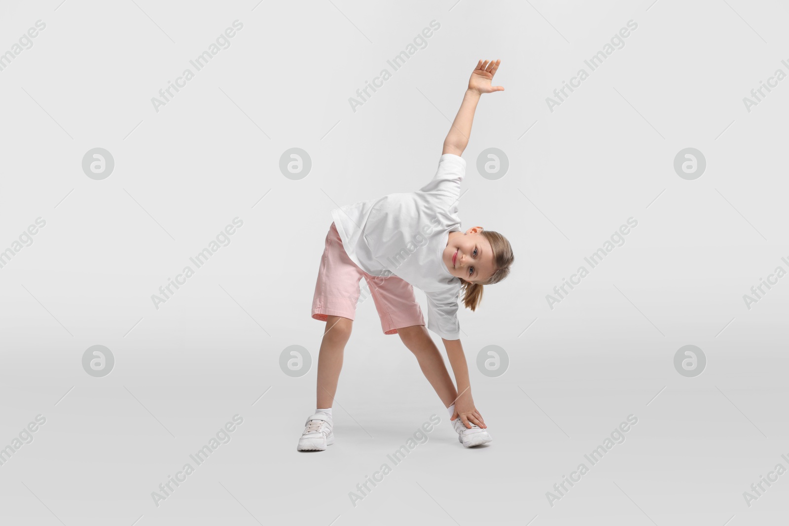 Photo of Cute little girl exercising on white background