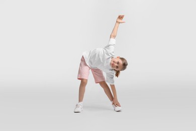 Cute little girl exercising on white background