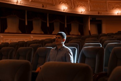 Photo of Young man watching theatrical performance in theatre