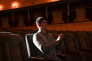 Portrait of young man applauding in theatre