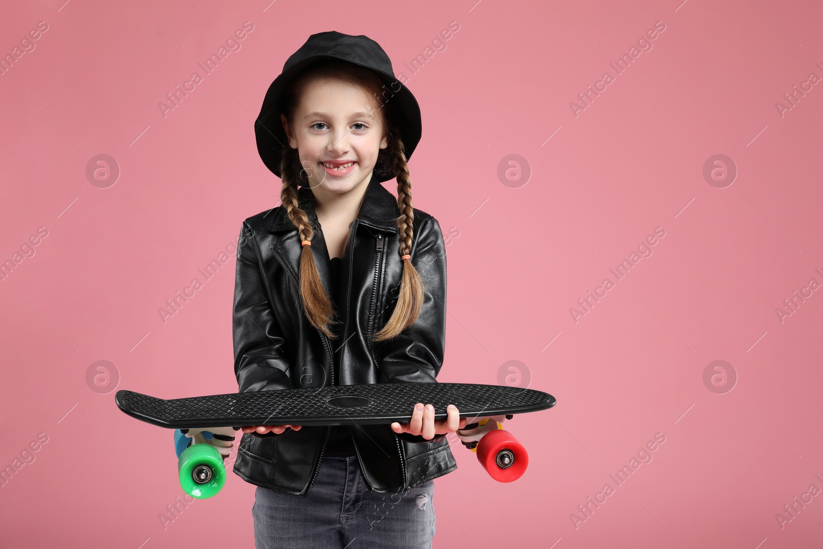 Photo of Little girl with penny board on pink background, space for text