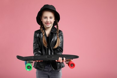 Little girl with penny board on pink background, space for text