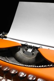 Photo of Vintage typewriter with sheet of paper on black background, closeup