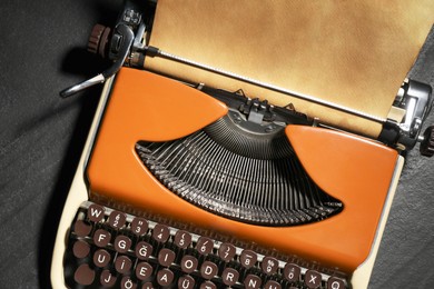 Photo of Vintage typewriter with parchment paper on black background, top view