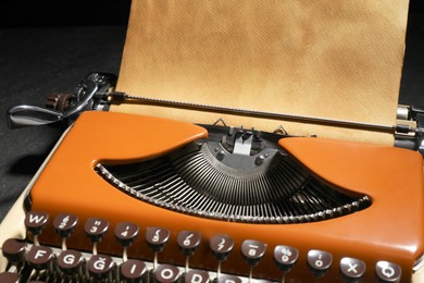 Photo of Vintage typewriter with parchment paper on black background, closeup