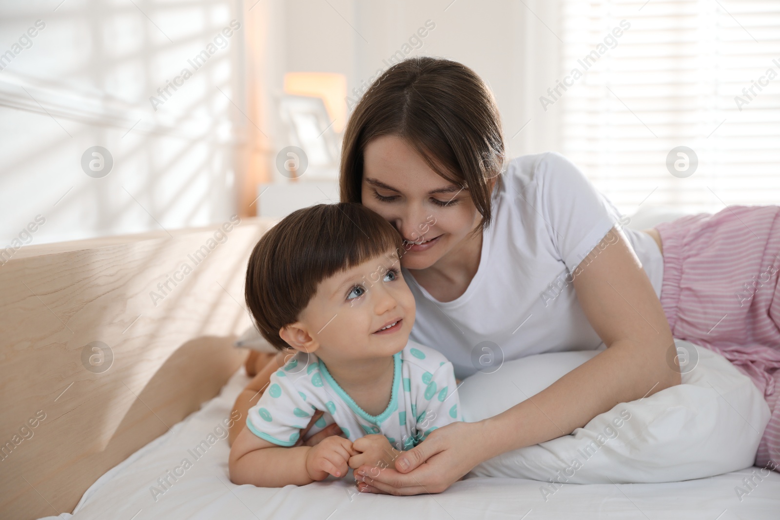 Photo of Happy mother with her little son on bed at home