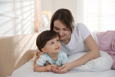 Photo of Happy mother with her little son on bed at home