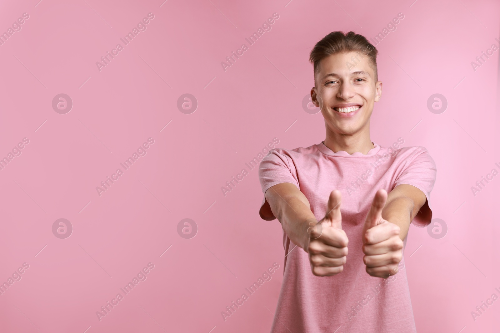 Photo of Happy man showing thumbs up on pink background, space for text. Like gesture