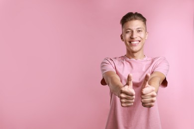 Happy man showing thumbs up on pink background, space for text. Like gesture