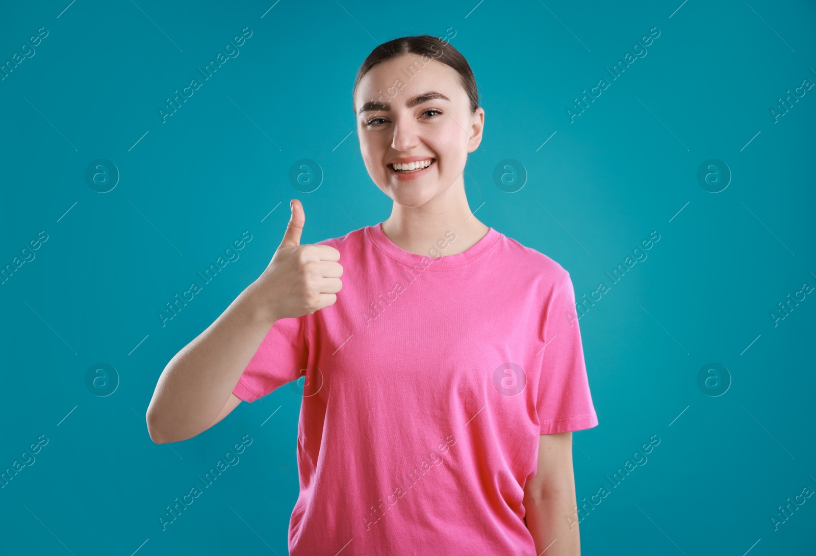 Photo of Happy woman showing thumbs up on light blue background. Like gesture