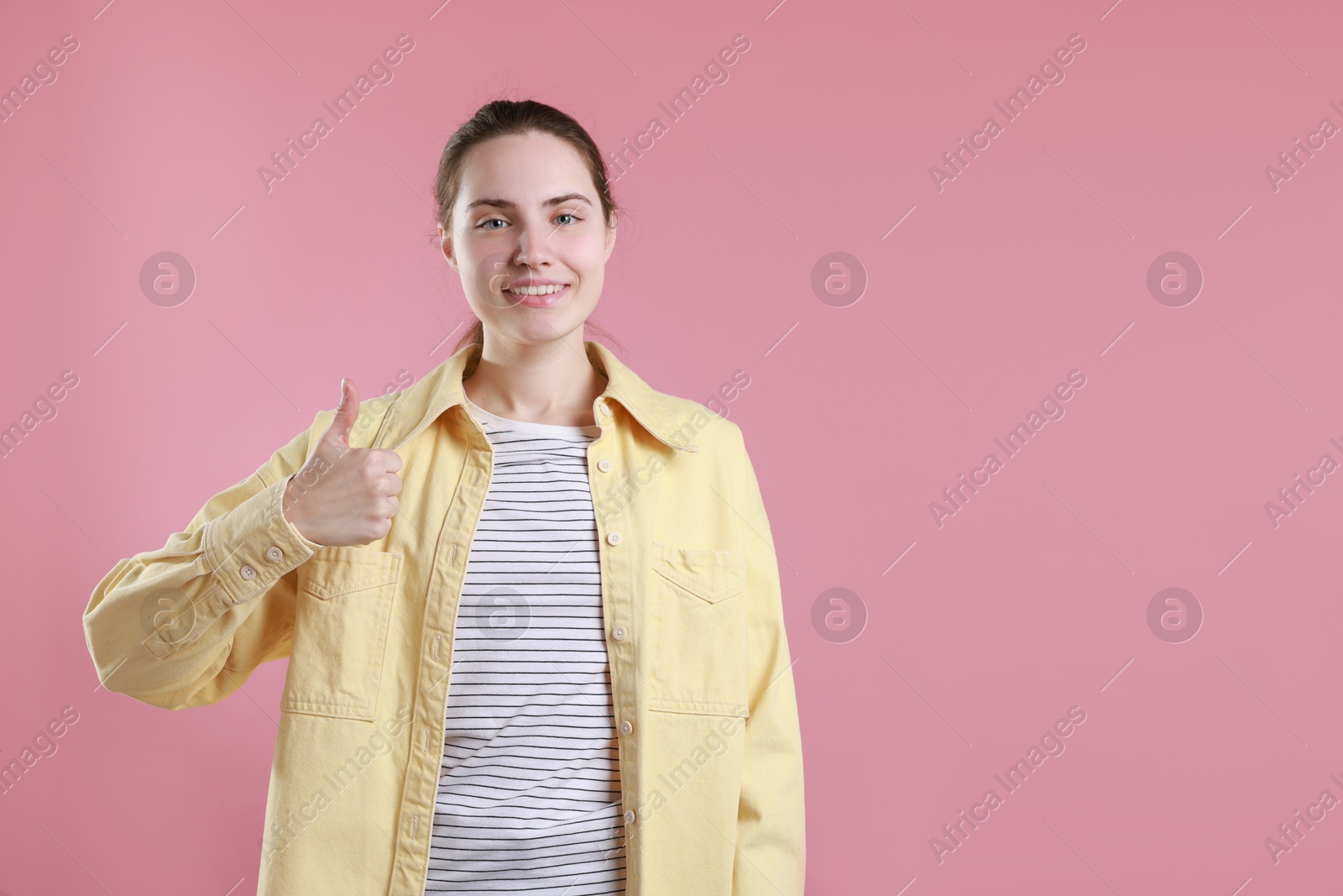 Photo of Happy woman showing thumbs up on pink background, space for text. Like gesture