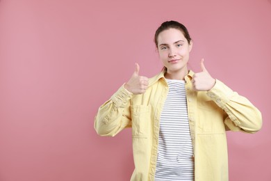 Woman showing thumbs up on pink background, space for text. Like gesture