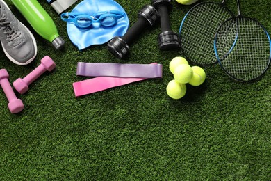 Photo of Different sports equipment on artificial grass, flat lay. Space for text