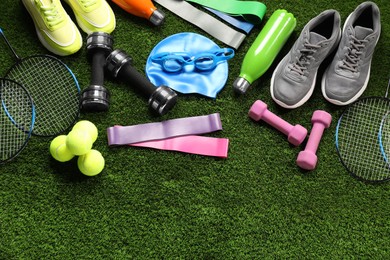 Photo of Different sports equipment on artificial grass, flat lay